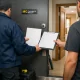 Cerrajero en Mataró entrega garantía junto a una puerta blindada recién instalada; residente y técnico aparecen de espaldas.
